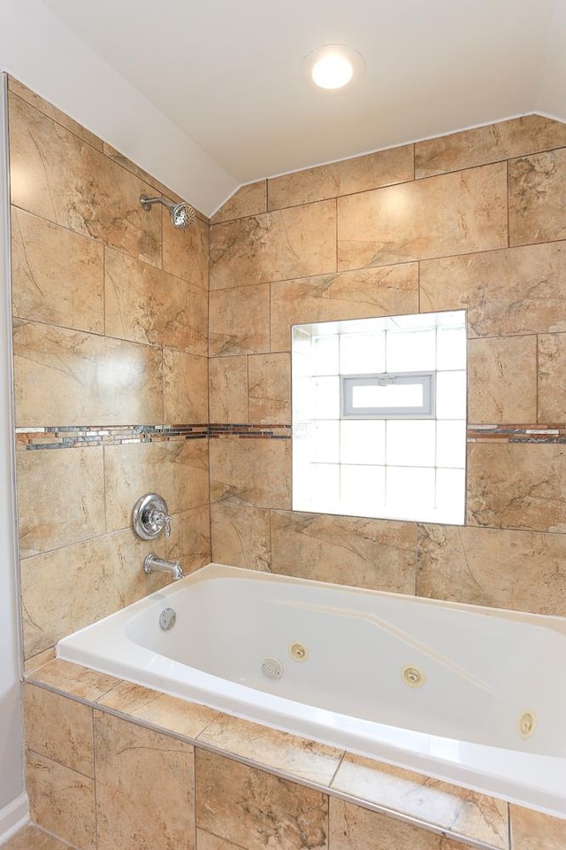 bathroom with tiled shower / bath combo and vaulted ceiling