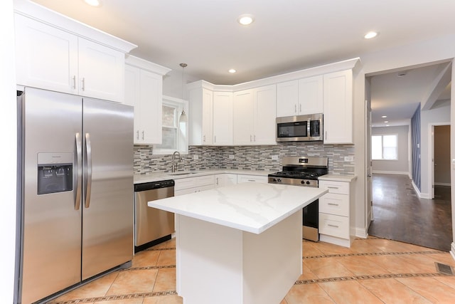 kitchen with sink, a center island, hanging light fixtures, light tile patterned floors, and appliances with stainless steel finishes