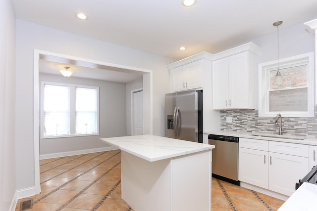 kitchen with sink, decorative light fixtures, appliances with stainless steel finishes, white cabinets, and backsplash