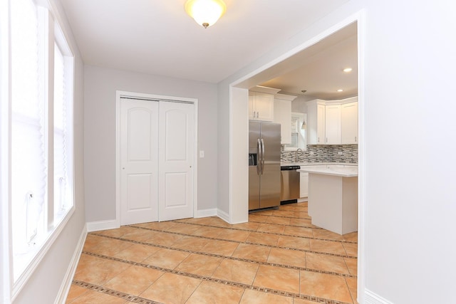 kitchen featuring light tile patterned floors, sink, appliances with stainless steel finishes, white cabinetry, and tasteful backsplash