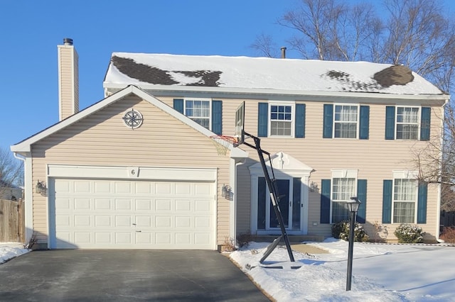 colonial house with a garage, a chimney, and aphalt driveway