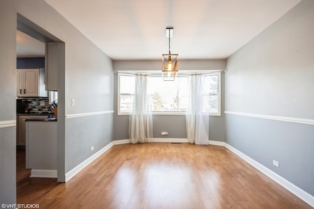 unfurnished dining area with light wood finished floors and baseboards