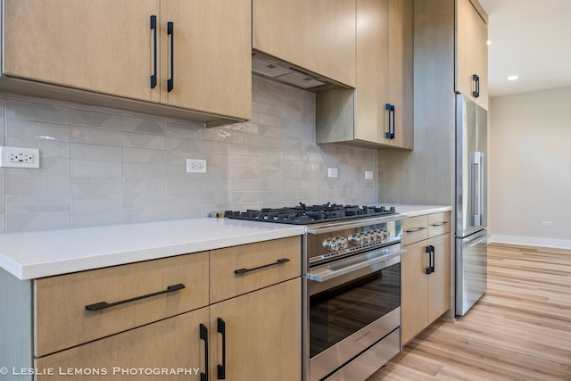 kitchen with light brown cabinetry, premium appliances, light hardwood / wood-style flooring, and a barn door