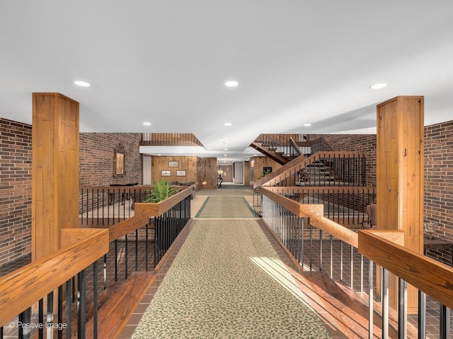 hallway featuring brick wall and wood-type flooring