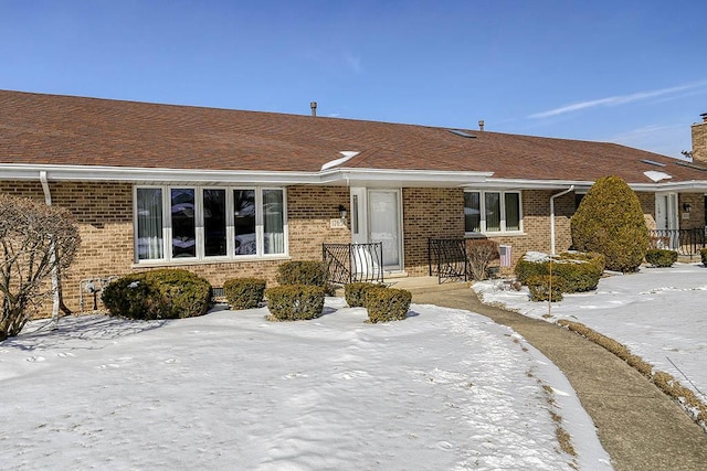 single story home featuring roof with shingles and brick siding