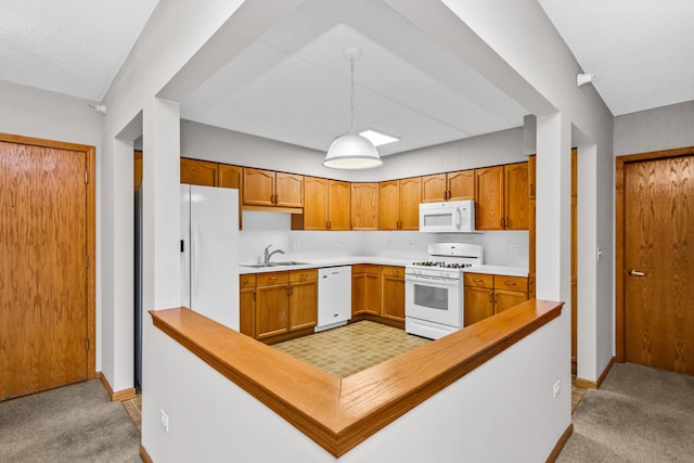 kitchen featuring sink, white appliances, hanging light fixtures, and light colored carpet