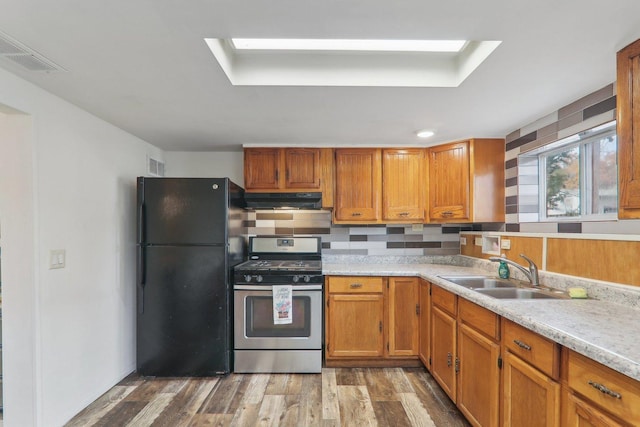 kitchen featuring sink, black refrigerator, stainless steel range with gas stovetop, and a skylight