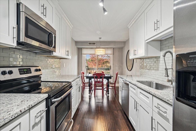 kitchen with appliances with stainless steel finishes, decorative light fixtures, and white cabinets