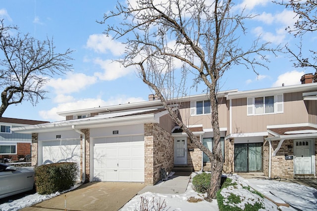 multi unit property featuring a garage, driveway, a chimney, and brick siding