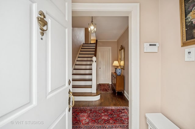 foyer with dark wood-style floors, a chandelier, and stairway