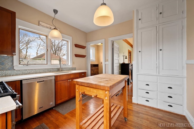 kitchen featuring light wood-style floors, light countertops, a sink, and stainless steel dishwasher