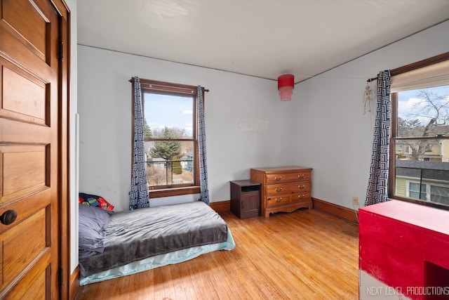 bedroom featuring light wood finished floors, multiple windows, and baseboards