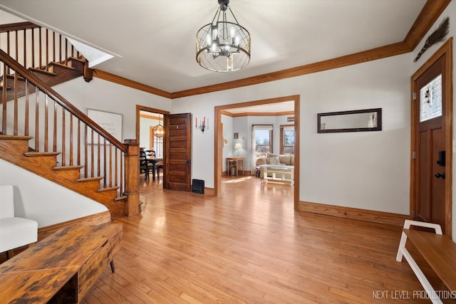 entrance foyer with an inviting chandelier, light wood-style flooring, stairs, and crown molding