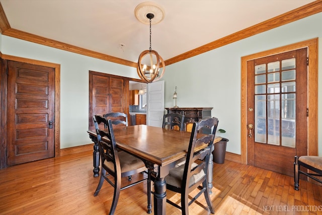 dining room with a notable chandelier, ornamental molding, and light wood-style floors