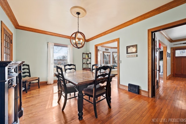 dining area featuring light wood-style floors, crown molding, baseboards, and a notable chandelier