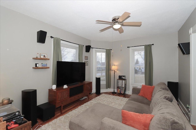 living area with ceiling fan, a textured ceiling, and wood finished floors