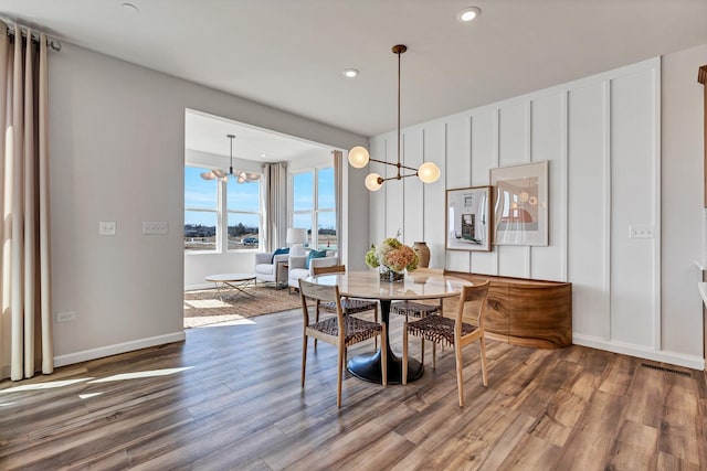 dining area with hardwood / wood-style floors and a notable chandelier