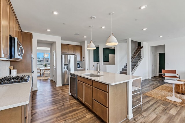 kitchen with dark wood-type flooring, sink, decorative light fixtures, an island with sink, and stainless steel appliances