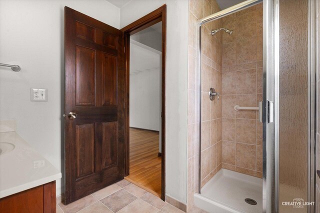 full bath featuring a shower stall, vanity, baseboards, and tile patterned flooring
