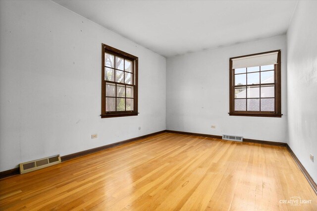spare room featuring plenty of natural light, wood finished floors, and baseboards