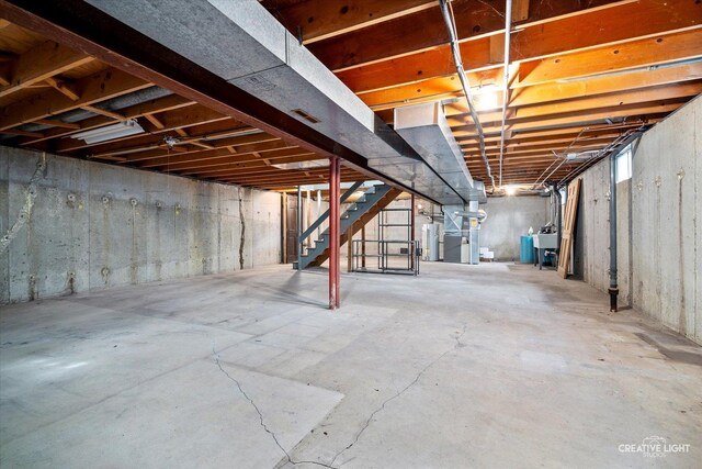 unfinished below grade area with gas water heater, stairs, heating unit, and a sink