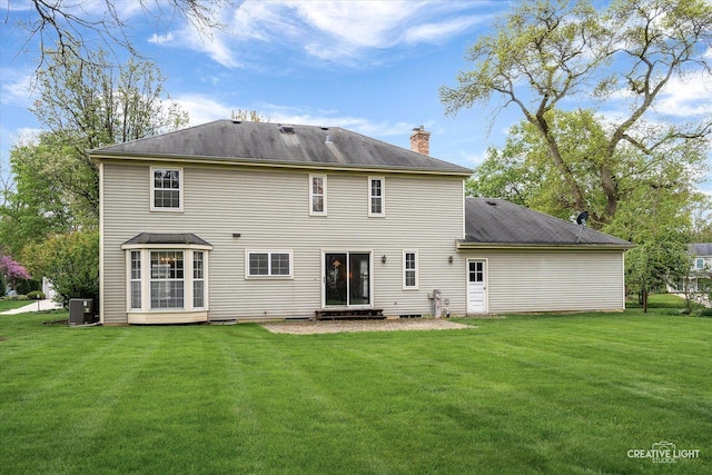 rear view of house with a chimney, central AC unit, and a lawn