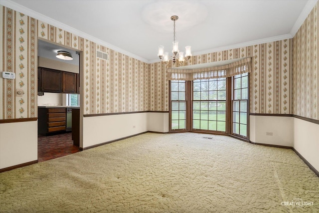 carpeted empty room with a chandelier, healthy amount of natural light, baseboards, wallpapered walls, and crown molding