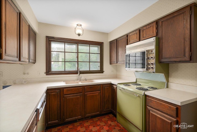 kitchen featuring white range with electric stovetop, a sink, wallpapered walls, and light countertops