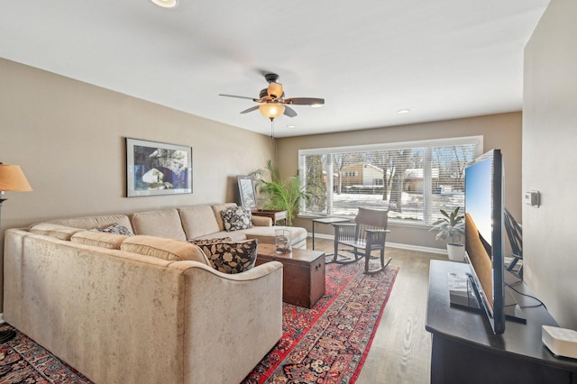 living room with wood finished floors, a ceiling fan, and baseboards