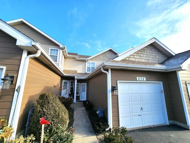 exterior space featuring an attached garage and a shingled roof