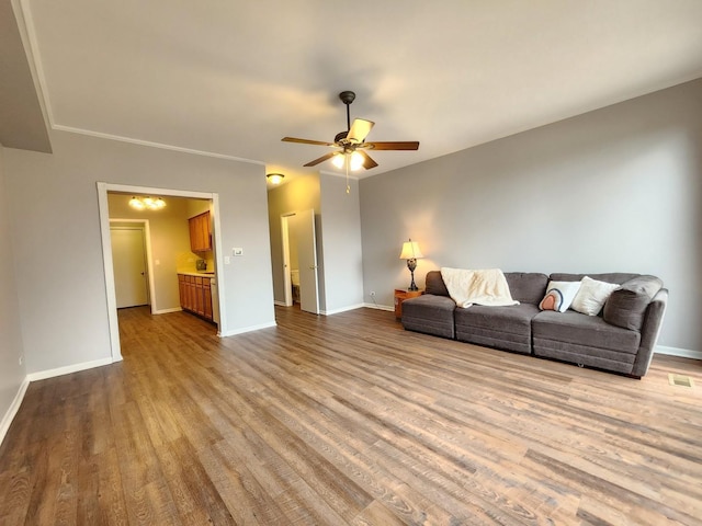 living room featuring a ceiling fan, visible vents, baseboards, and wood finished floors