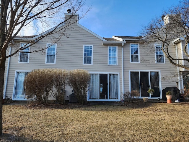 back of house featuring a chimney, central AC unit, and a yard