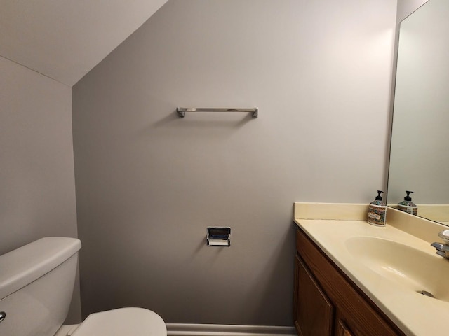 half bath featuring toilet, vaulted ceiling, and vanity