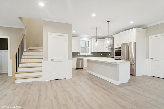 kitchen featuring a center island, pendant lighting, stainless steel appliances, light hardwood / wood-style floors, and white cabinets