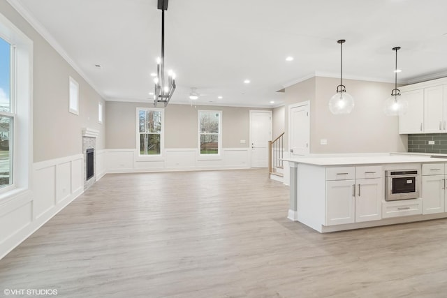 kitchen with decorative backsplash, white cabinetry, oven, and decorative light fixtures