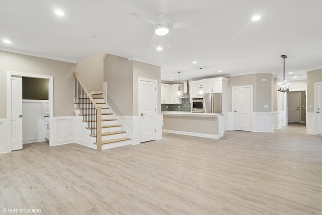 unfurnished living room with ceiling fan, crown molding, and light wood-type flooring