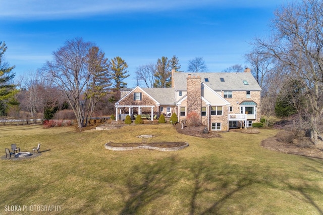 back of property with an outdoor fire pit, a pergola, and a lawn