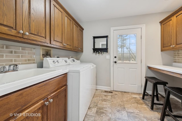 clothes washing area with cabinets, separate washer and dryer, and sink