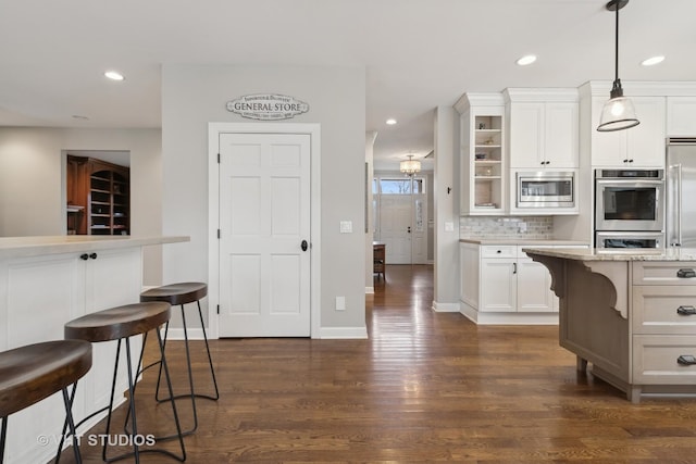 kitchen with stainless steel microwave, decorative light fixtures, a breakfast bar, and white cabinets