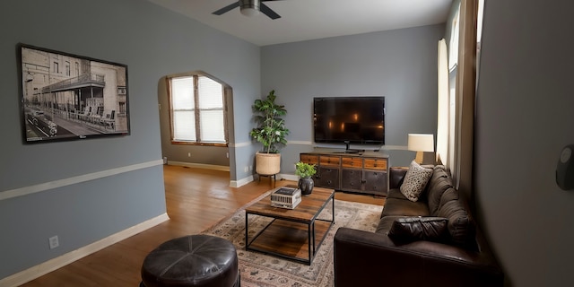 living room featuring light wood finished floors, baseboards, and a ceiling fan