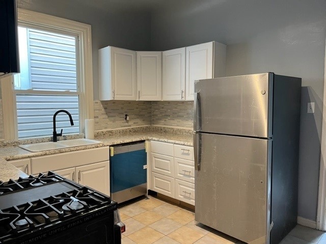kitchen with dishwashing machine, freestanding refrigerator, a sink, black range with gas stovetop, and white cabinetry