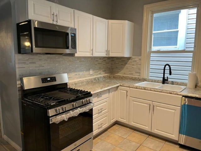 kitchen with decorative backsplash, white cabinets, stainless steel appliances, and a sink