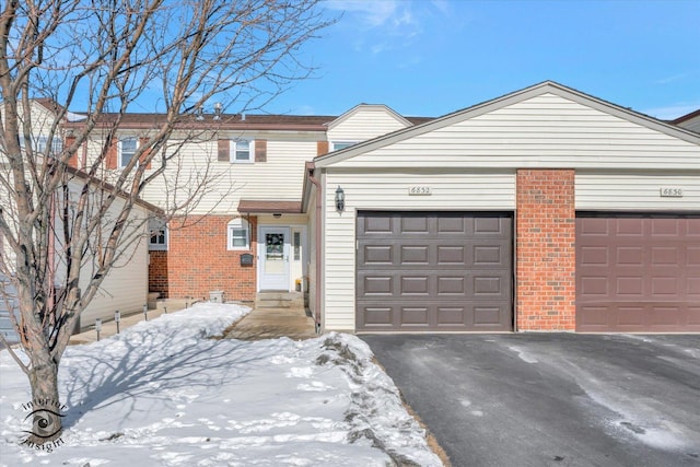 view of front of home with aphalt driveway, entry steps, brick siding, and an attached garage