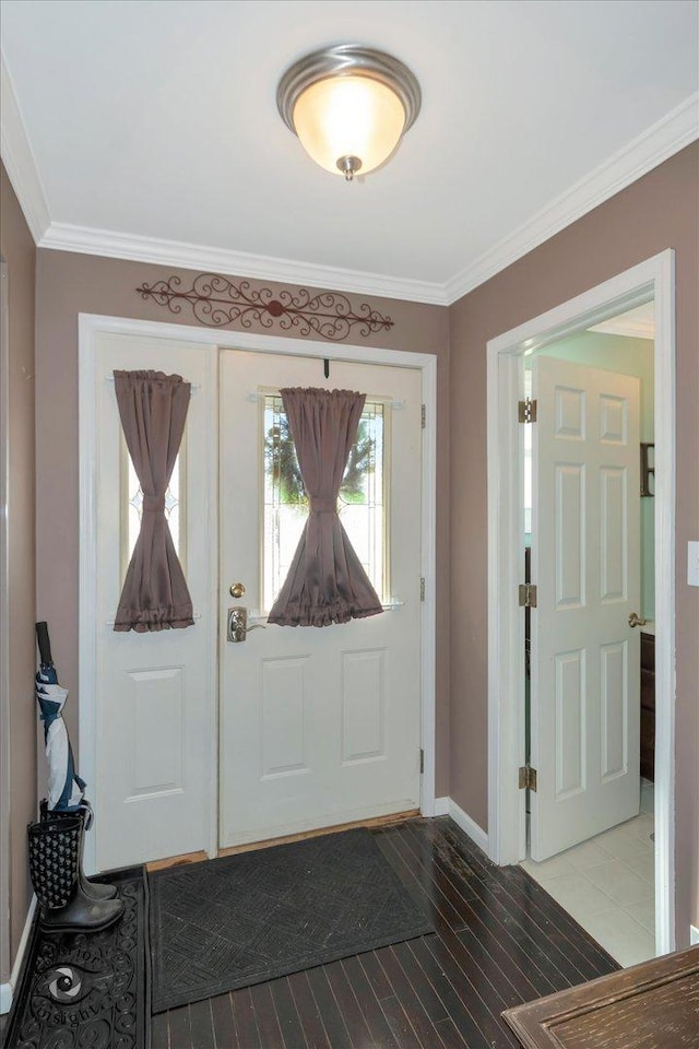 foyer entrance featuring ornamental molding, wood finished floors, and baseboards