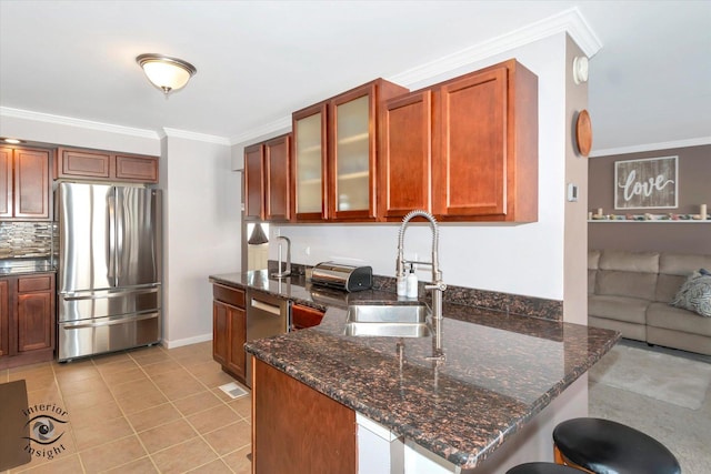 kitchen with glass insert cabinets, freestanding refrigerator, dark stone counters, and a sink