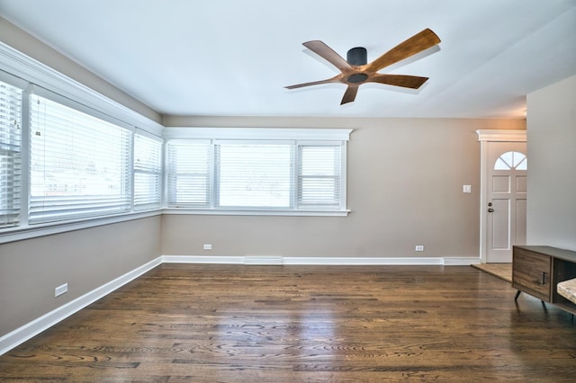 spare room featuring dark wood-type flooring, ceiling fan, and a wealth of natural light