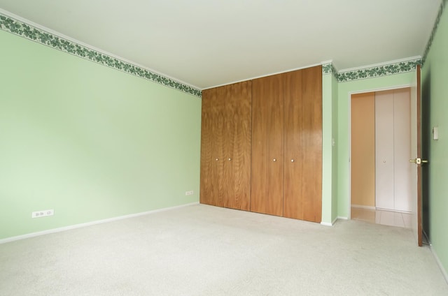 unfurnished bedroom with crown molding, light colored carpet, and a closet