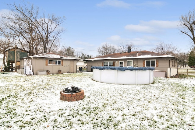 snow covered house with a covered pool and an outdoor fire pit