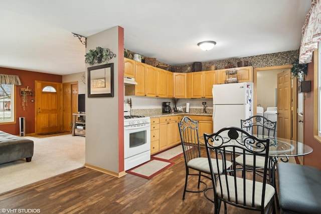 kitchen featuring dark wood-type flooring, white appliances, light brown cabinetry, and washing machine and clothes dryer