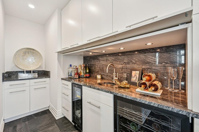 kitchen with wine cooler, white cabinetry, dark stone counters, and a sink